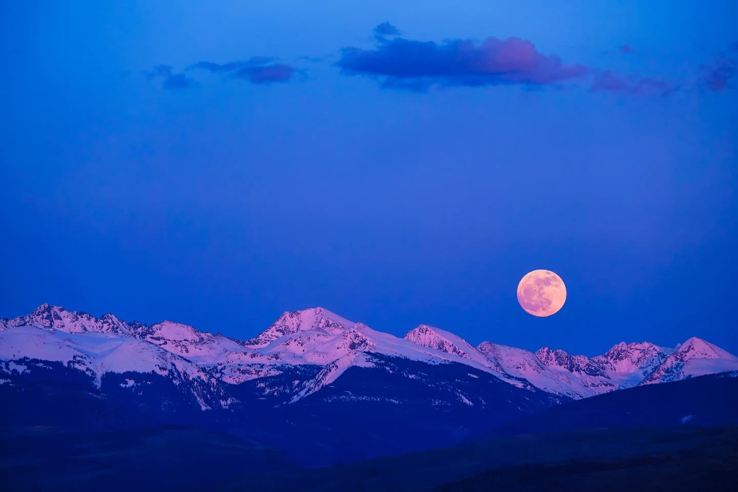 Moon rising over snow-capped mountains